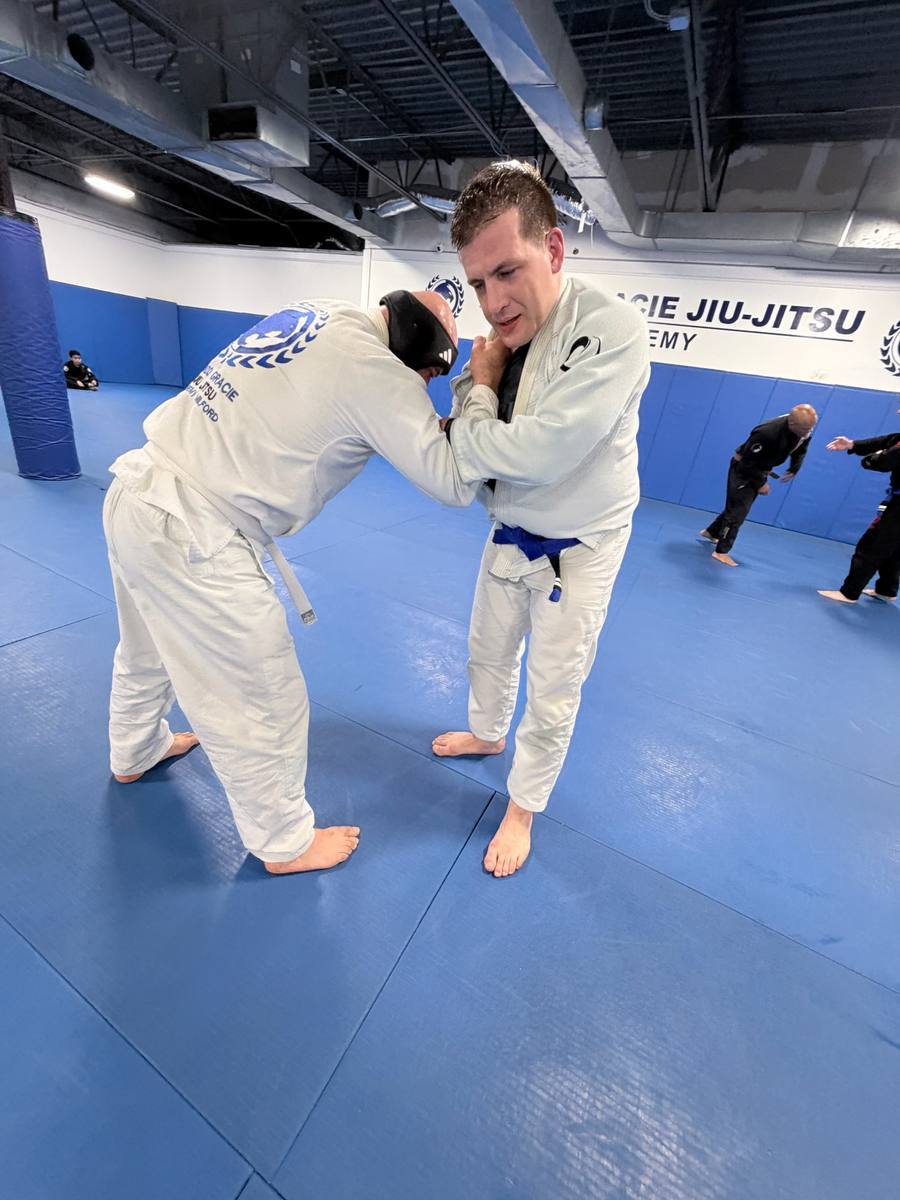 Two adult students in white gis gripping during class
