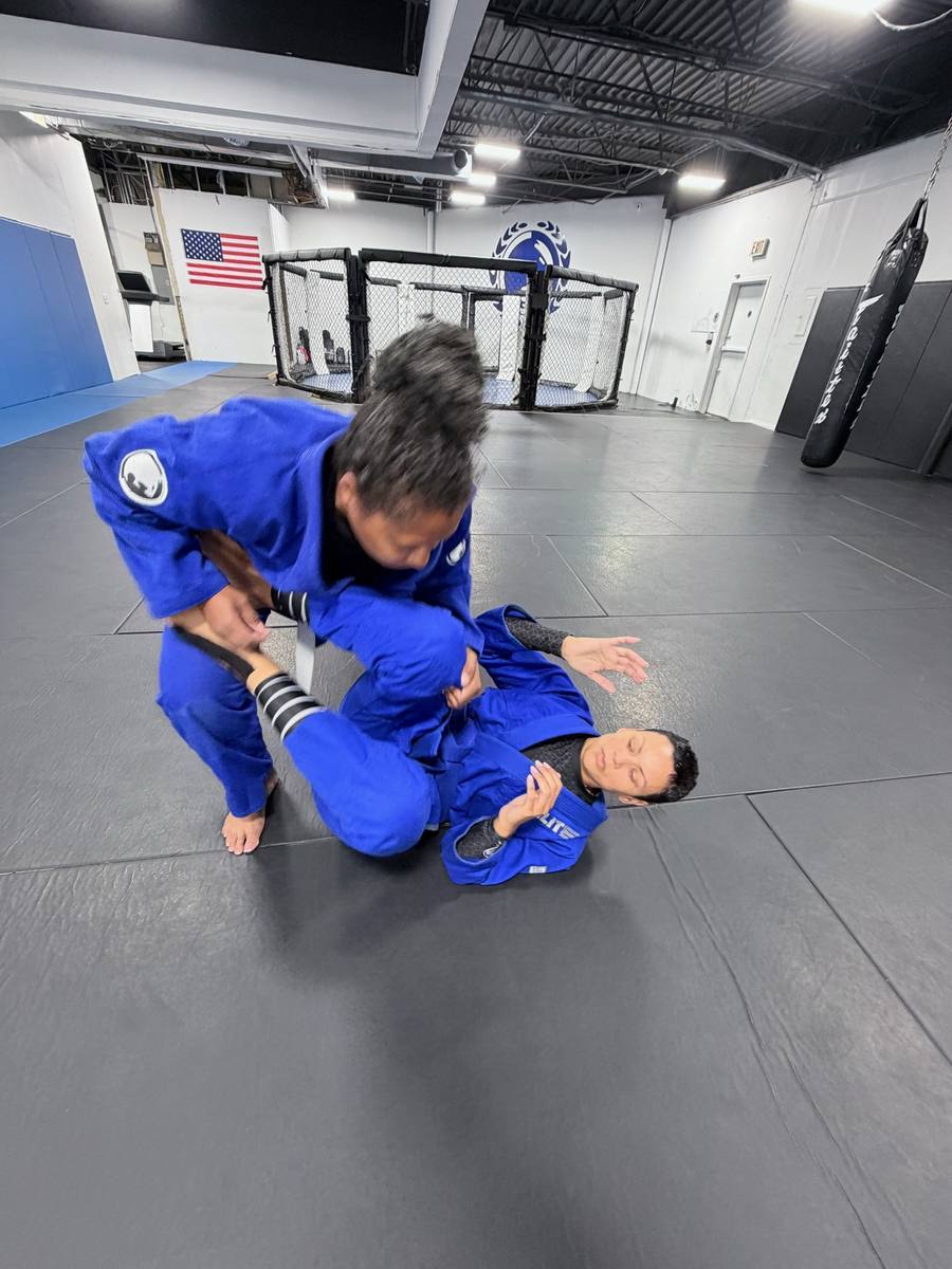 Students in blue gis training guard on the mat