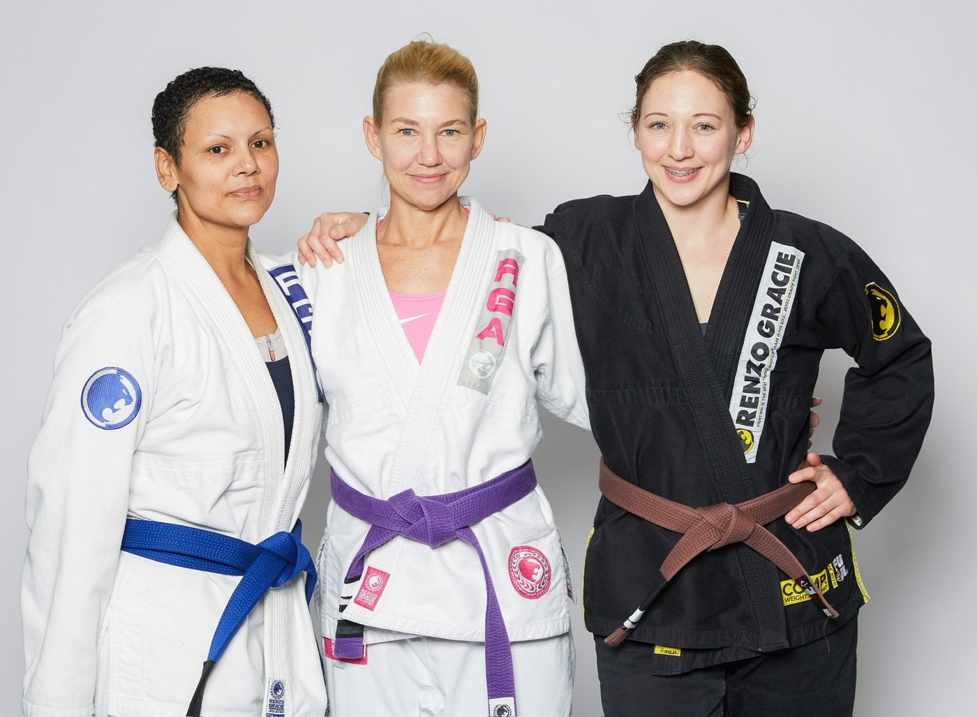 Three women members of Renzo Gracie Milford in gis with blue, purple and brown belts